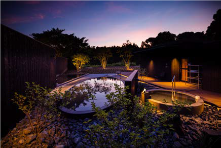 An oval-shaped open-air bath looks over the native-grown cherry blossom trees